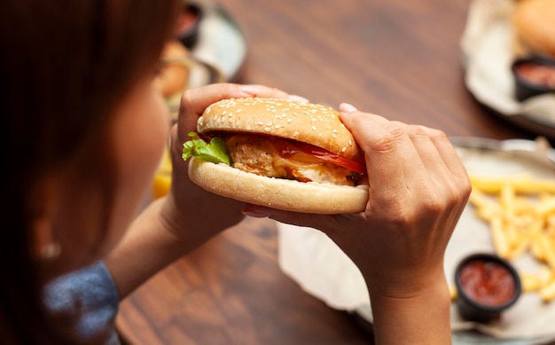 Mulher comendo hambúrguer em ângulo alto