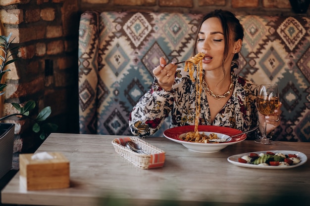 Mulher comendo macarrão em restaurante italiano