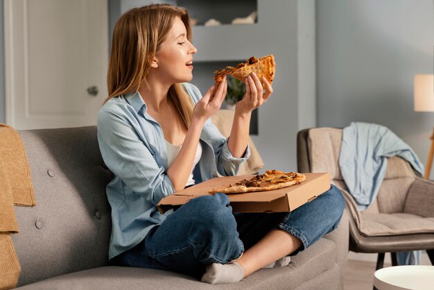 Mulher comendo pizza enquanto assiste tv