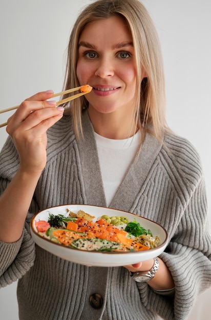 Foto grátis mulher comendo prato de frutos do mar com salmão