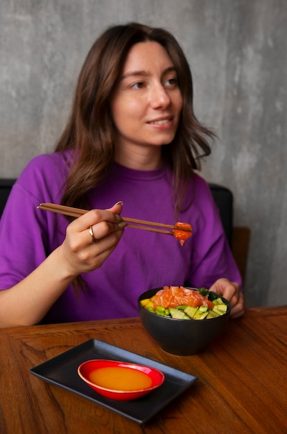 Foto grátis mulher comendo tigela de prato de salmão no restaurante