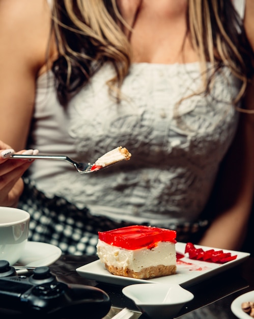 mulher comendo um delicioso cheesecake de morango