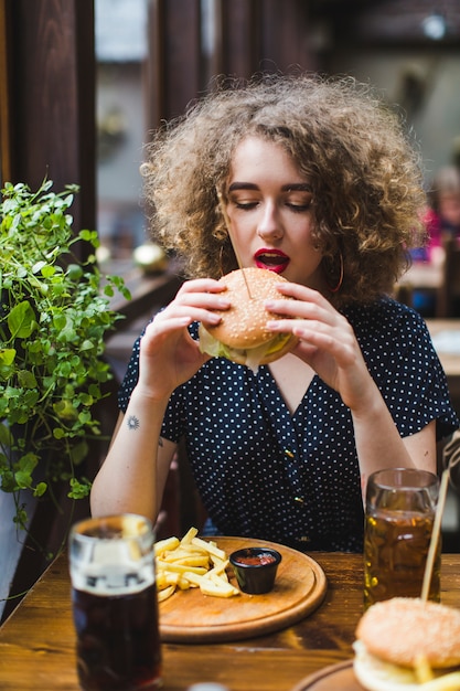 Mulher, comer, hamburger, em, restaurante