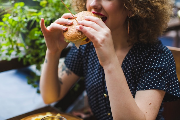 Mulher, comer, hamburger, em, restaurante