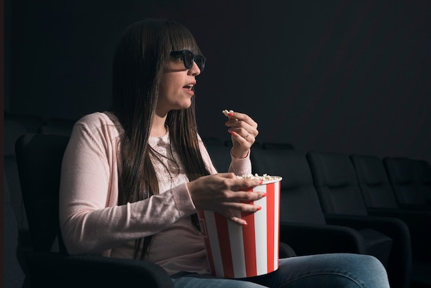 Foto grátis mulher, comer, pipoca, em, cinema