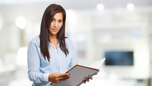 Mulher concentrada que lê um caderno aberto