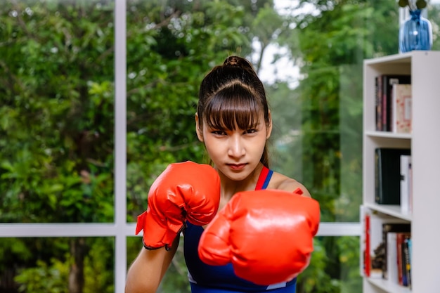 Mulher confiante atleta posando com luvas de boxe, olhando para a câmera