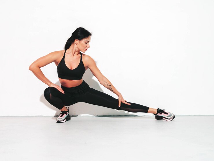 Foto grátis mulher confiante em fitness em roupas esportivas sexy jovem modelo bonito com corpo perfeito mulher posando no estúdio esticando-se antes do treino