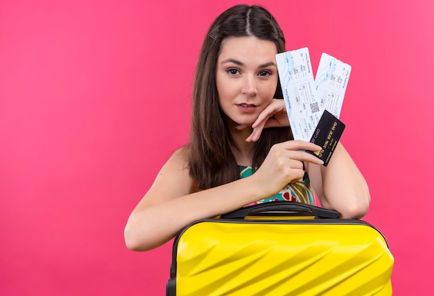 Foto grátis mulher confiante jovem viajante segurando mala e bilhetes na parede rosa isolada