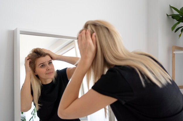 Mulher confusa de tiro médio olhando no espelho