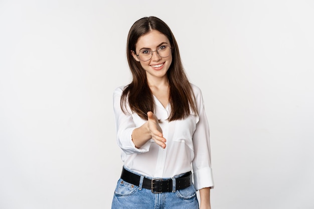 Foto grátis mulher corporativa no escritório, estendendo a mão e sorrindo, cumprimentando o parceiro de negócios em pé...