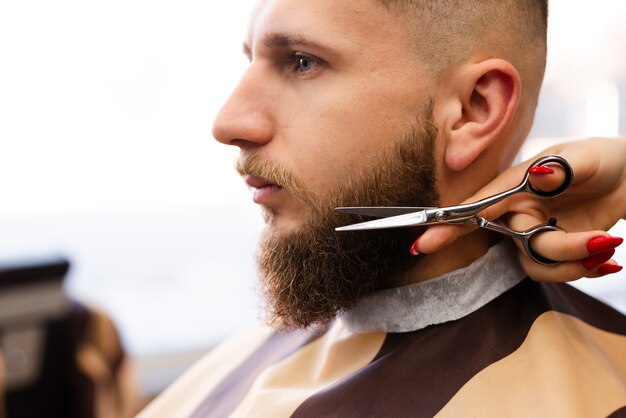 Mulher cortando a barba de um homem em uma barbearia profissional