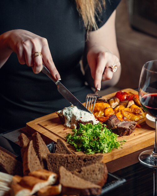 mulher cortando bife com queijo cheddar derretido e molho cremoso