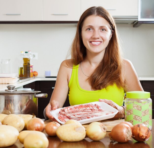 Mulher cozinhando com carne de cordeiro