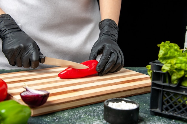 Foto grátis mulher cozinheira cortando pimenta vermelha na comida cinza cozinhando salada