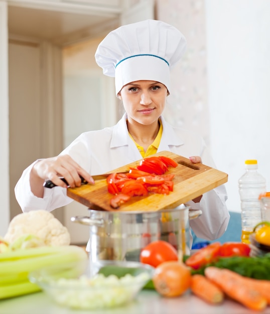 Mulher cozinheira em toque funciona em cozinha comercial