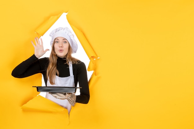 Mulher cozinheira segurando uma panela preta com biscoitos em amarelo foto emoção comida cozinha cozinha cor trabalho
