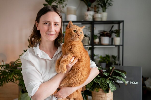 Mulher cultivando plantas em casa segurando um gato