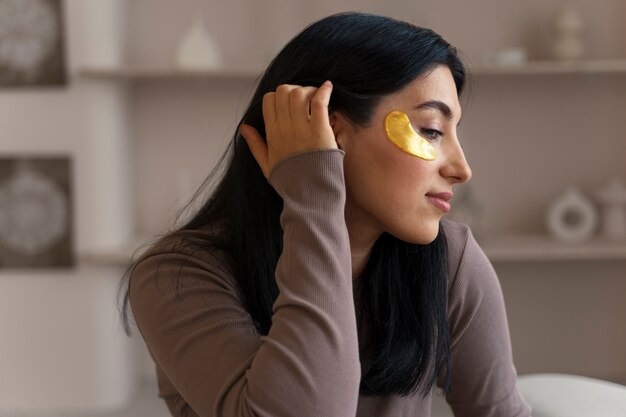 Mulher curtindo sua rotina de beleza com tapa-olhos dourados