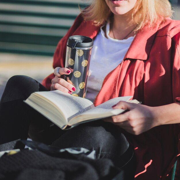 Mulher da colheita que aprecia o livro e bebe