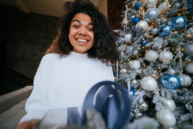 Mulher dá um presente para seu amigo na câmera Retrato de uma jovem de aparência afro morena de cabelo encaracolado preto étnico