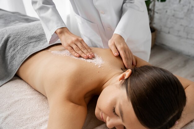 Mulher de alto ângulo a ser massageada no spa.