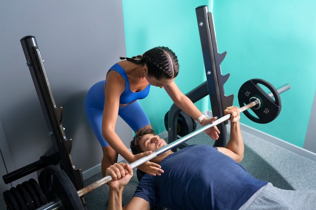 Foto grátis mulher de alto ângulo ajudando a caber o homem na academia