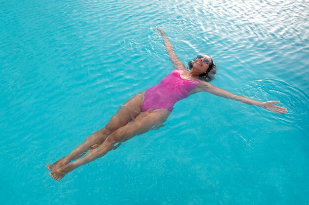 Mulher de alto ângulo flutuando na piscina