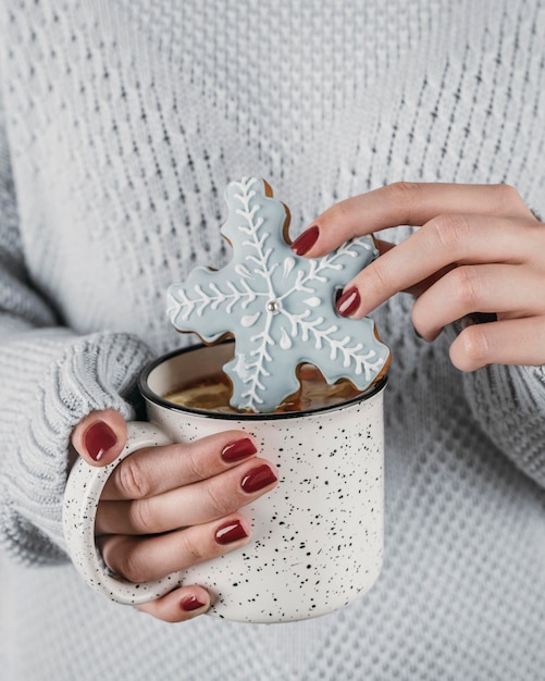 Mulher de alto ângulo mergulhando biscoito de floco de neve em chocolate quente