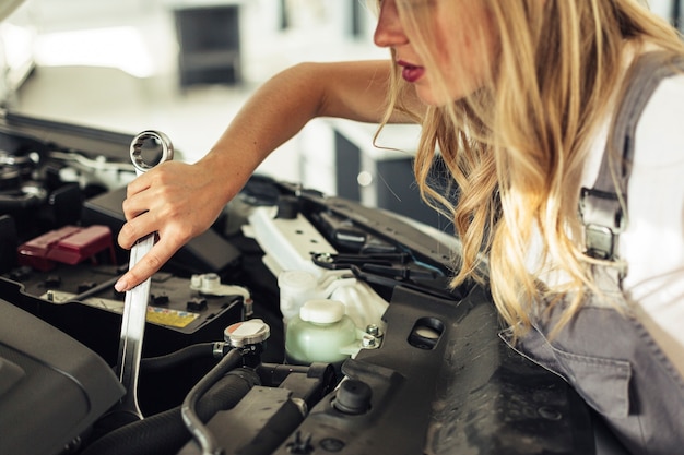 Mulher de alto ângulo, reparando o motor do carro