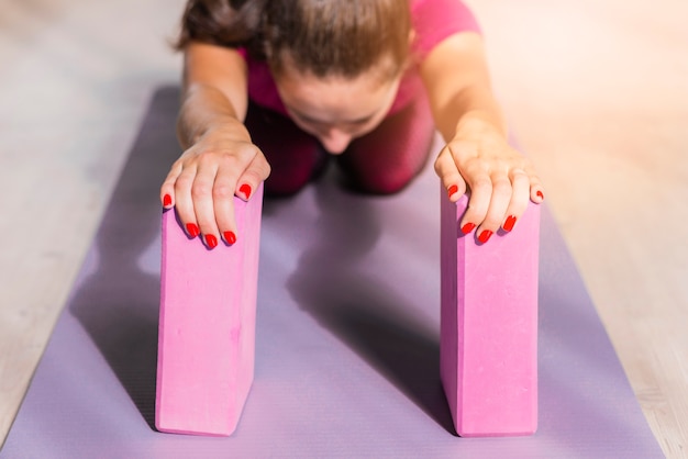 Mulher de aptidão desportiva praticando ioga com blocos-de-rosa na esteira de exercícios