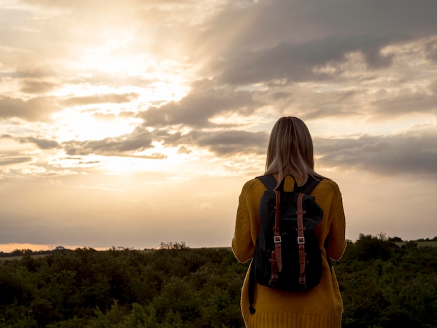 Foto grátis mulher de baixo ângulo ao pôr do sol na montanha