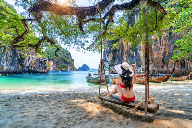 Mulher de biquíni relaxando no balanço na ilha de embarque de ko lao, krabi, tailândia