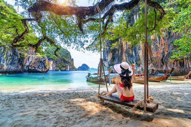 Mulher de biquíni relaxando no balanço na ilha de embarque de Ko lao, Krabi, Tailândia