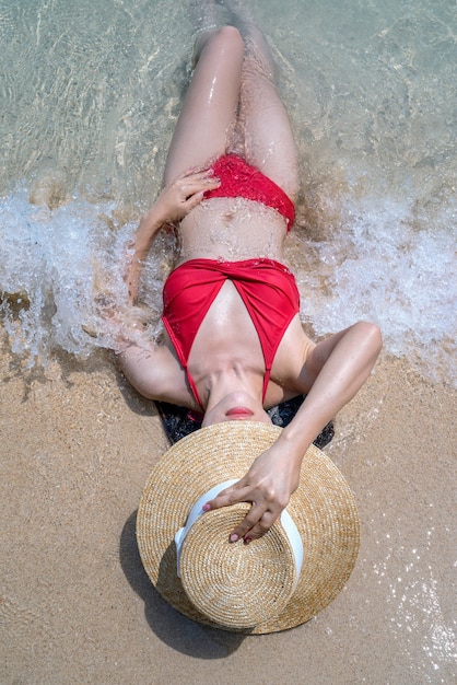 Mulher de biquíni relaxante na praia, Railay, na Tailândia.