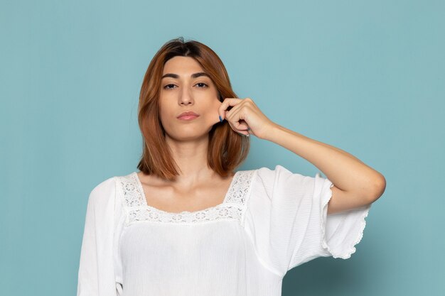 mulher de blusa branca e jeans azul puxando a bochecha