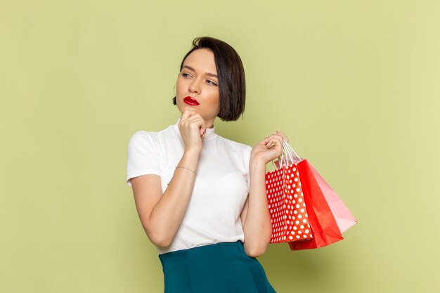 mulher de blusa branca e saia verde segurando pacotes de compras