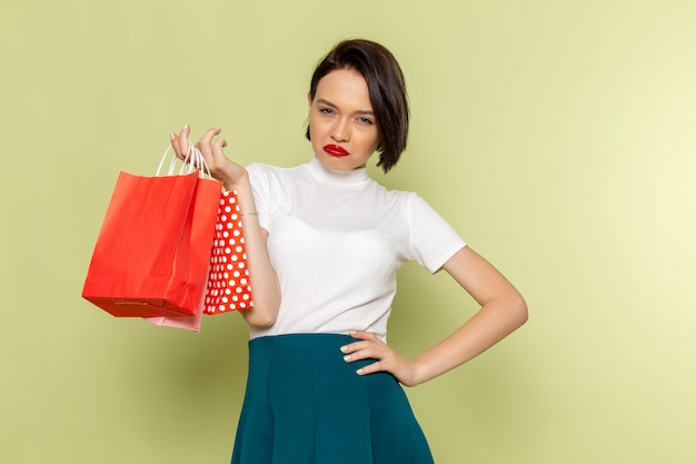 Foto grátis mulher de blusa branca e saia verde segurando pacotes de compras