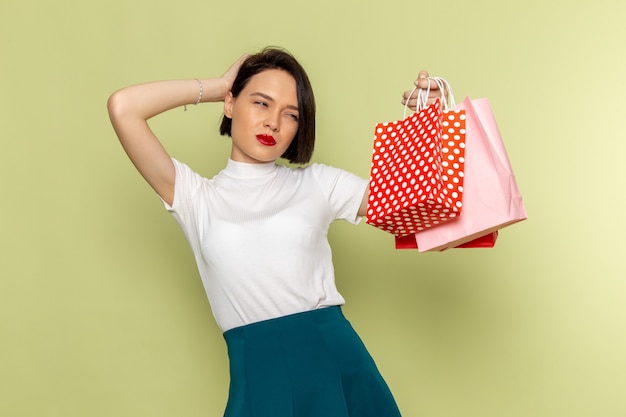 mulher de blusa branca e saia verde segurando pacotes de compras