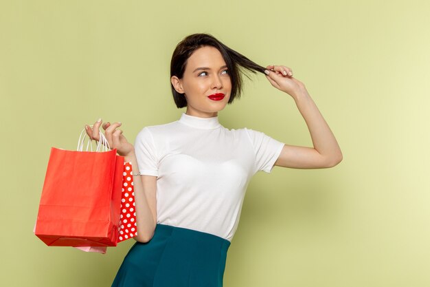 mulher de blusa branca e saia verde segurando pacotes de compras