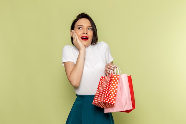 mulher de blusa branca e saia verde segurando pacotes de compras