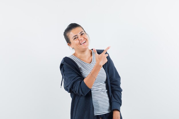 Mulher de cabelo escuro apontando para longe enquanto sorri com uma camisa