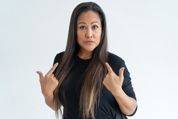 Mulher de cabelo preto surpreso apontando para si mesma