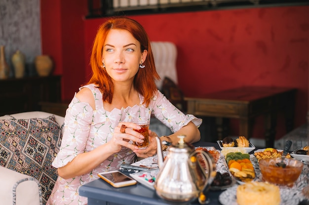 Mulher de cabelo vermelho, bebendo chá no restaurante