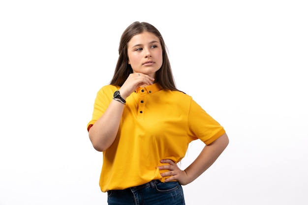 Mulher de camisa amarela e calça jeans posando com expressão de pensamento nas roupas de modelo de mulher de fundo branco