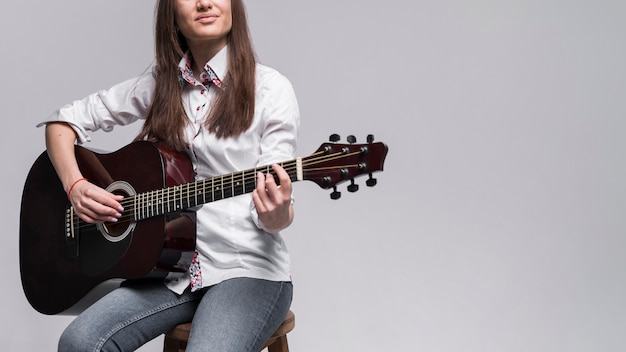 Mulher de camisa branca, tocando violão