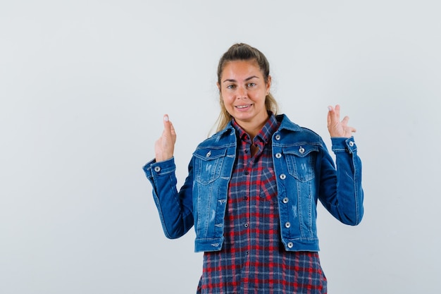 Mulher de camisa, jaqueta mostrando gesto de meditação e olhando alegre, vista frontal.