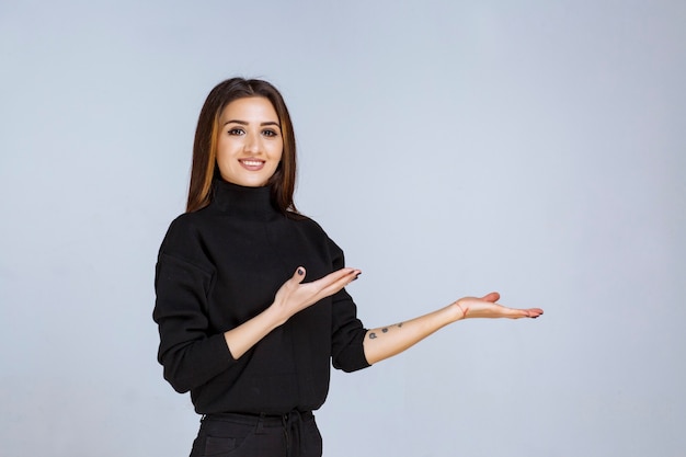 Foto grátis mulher de camisa preta apontando algo à direita.