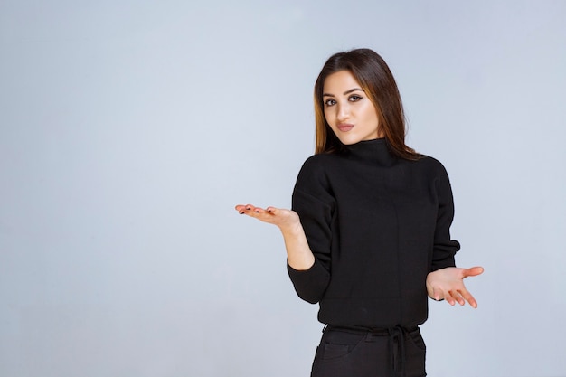 Mulher de camisa preta dando poses neutras e sedutoras.