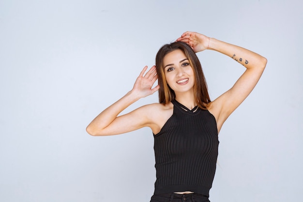 Mulher de camisa preta dando poses positivas e sedutoras.